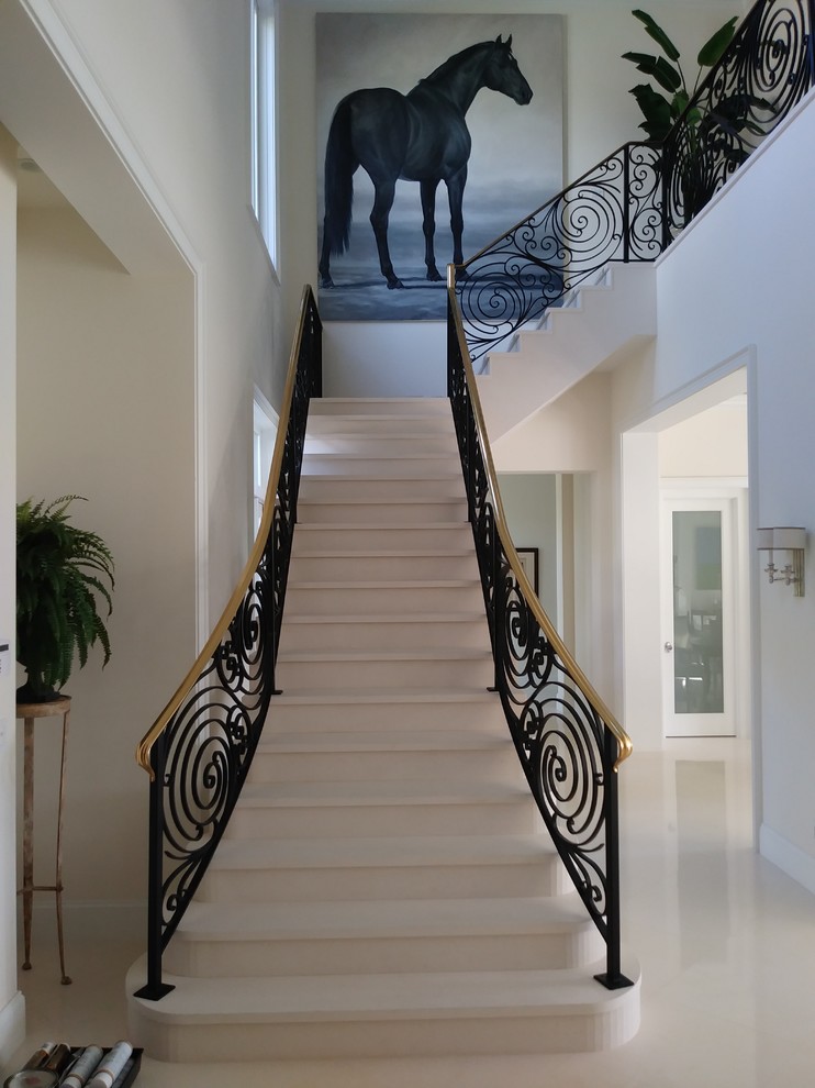 Пример оригинального дизайна: большая угловая лестница в современном стиле с металлическими перилами, мраморными ступенями и подступенками из мрамора
