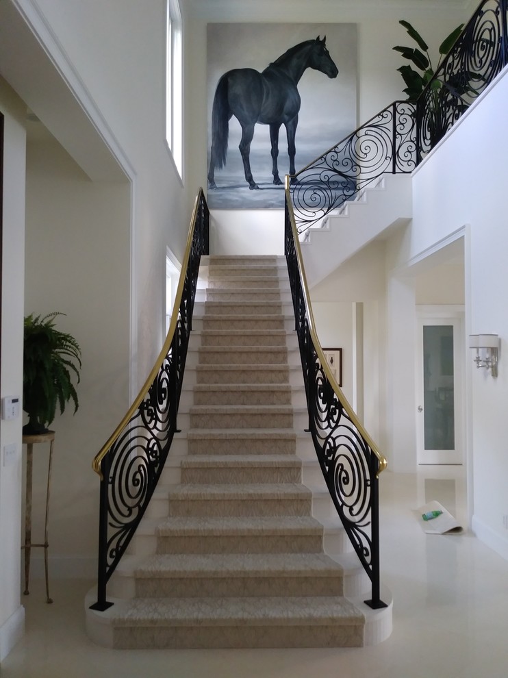 Réalisation d'un grand escalier design en L et marbre avec des contremarches en marbre et un garde-corps en métal.