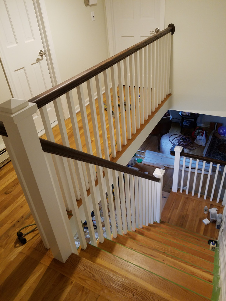 Aménagement d'un grand escalier classique en L avec des marches en bois, des contremarches en bois et un garde-corps en bois.