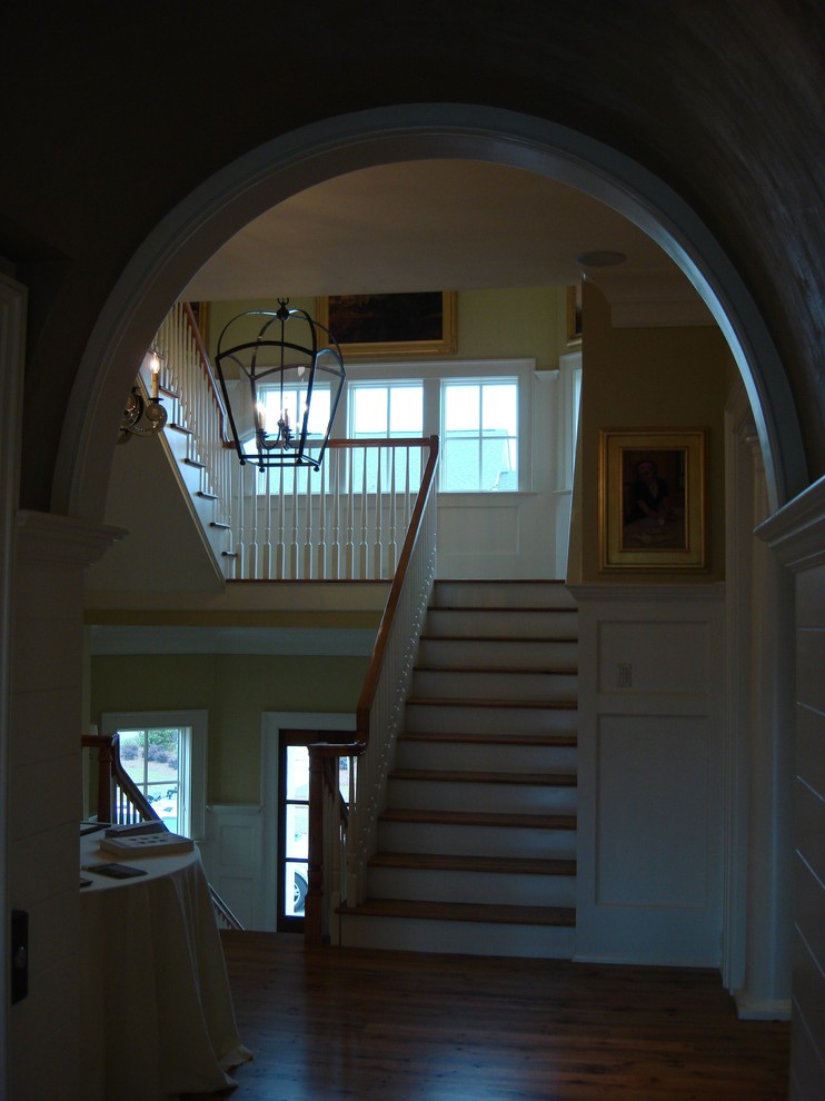На фото: п-образная лестница среднего размера в морском стиле с деревянными ступенями, крашенными деревянными подступенками, деревянными перилами и панелями на стенах с