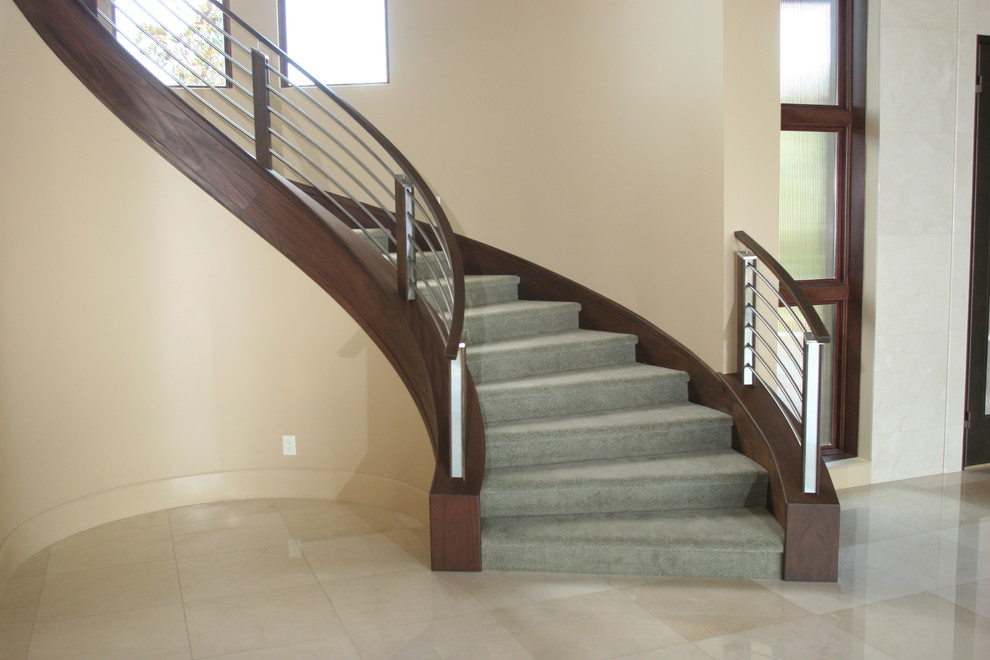 Пример оригинального дизайна: изогнутая лестница в стиле модернизм с ступенями с ковровым покрытием и ковровыми подступенками