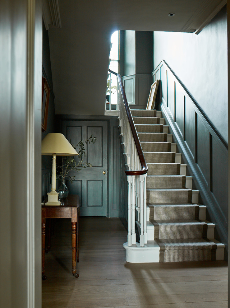 Exemple d'un grand escalier chic en U avec des marches en moquette, des contremarches en moquette, un garde-corps en bois et éclairage.
