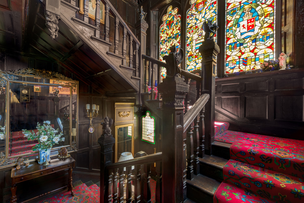 Example of a huge ornate carpeted l-shaped staircase design in Devon with wooden risers
