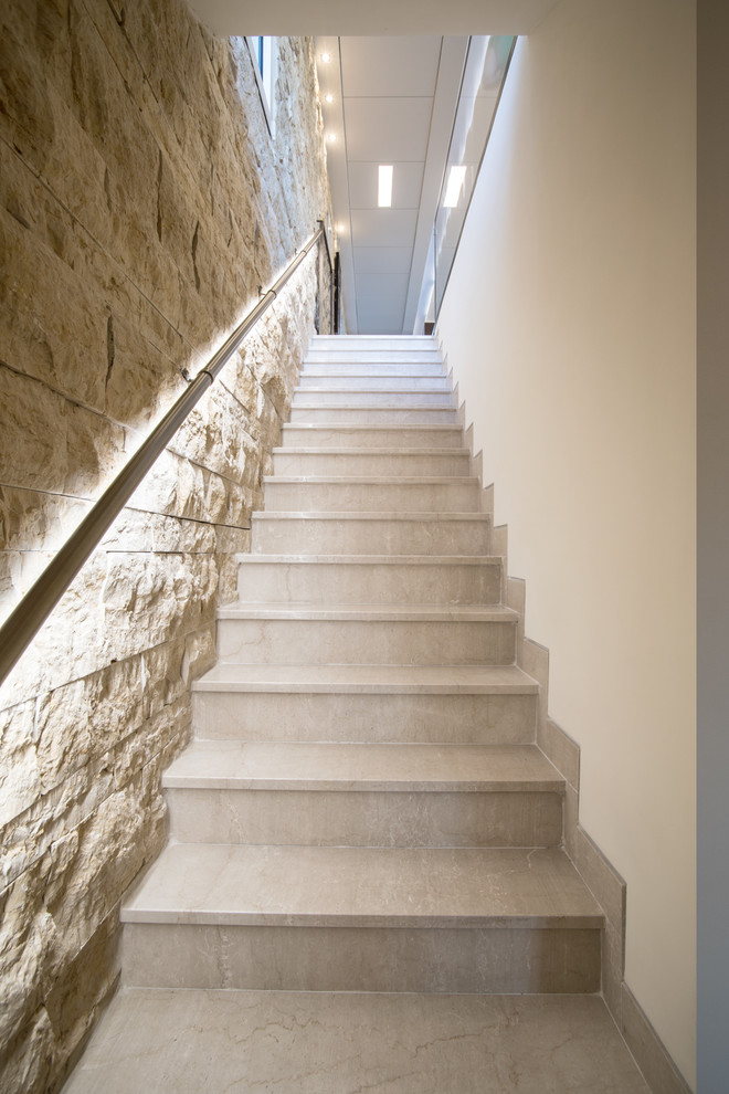 На фото: прямая лестница среднего размера в стиле модернизм с ступенями из травертина, подступенками из травертина и перилами из смешанных материалов с