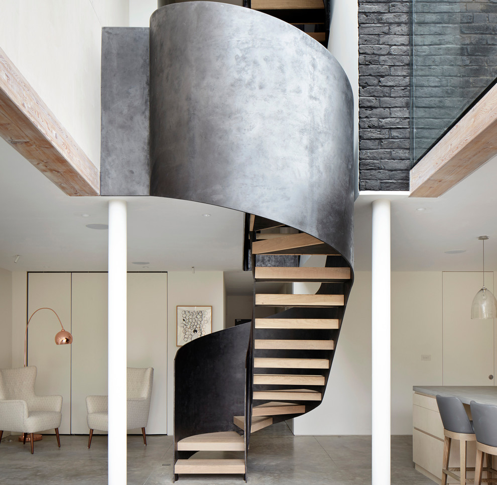 Idée de décoration pour un grand escalier sans contremarche courbe design avec des marches en bois et un garde-corps en métal.