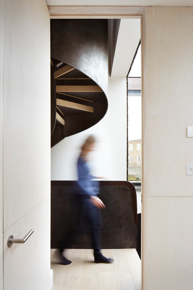 Стильный дизайн: большая изогнутая лестница в современном стиле с деревянными ступенями и металлическими перилами без подступенок - последний тренд