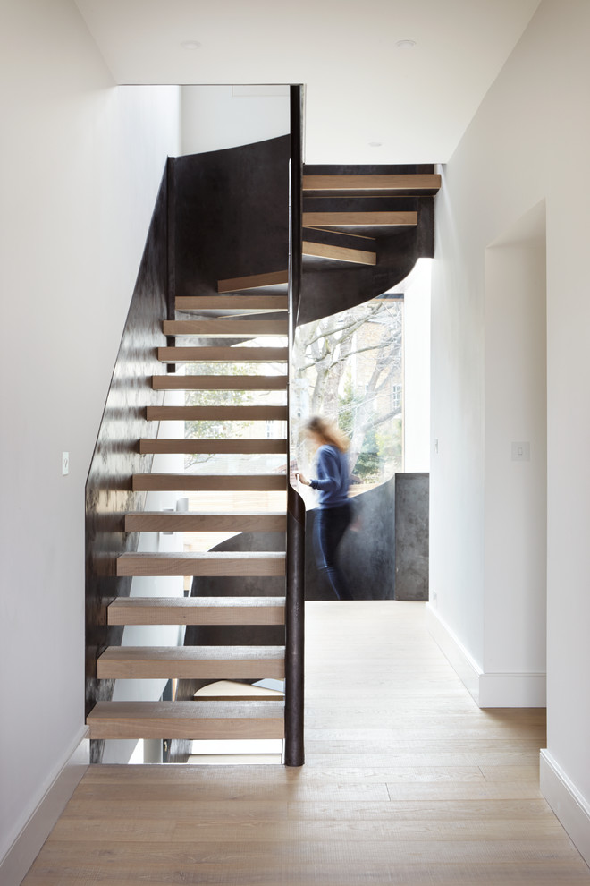 Photo of a contemporary wood u-shaped metal railing staircase in London with open risers.