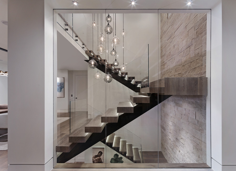 Idée de décoration pour un escalier sans contremarche design en U avec des marches en bois, un garde-corps en verre et éclairage.