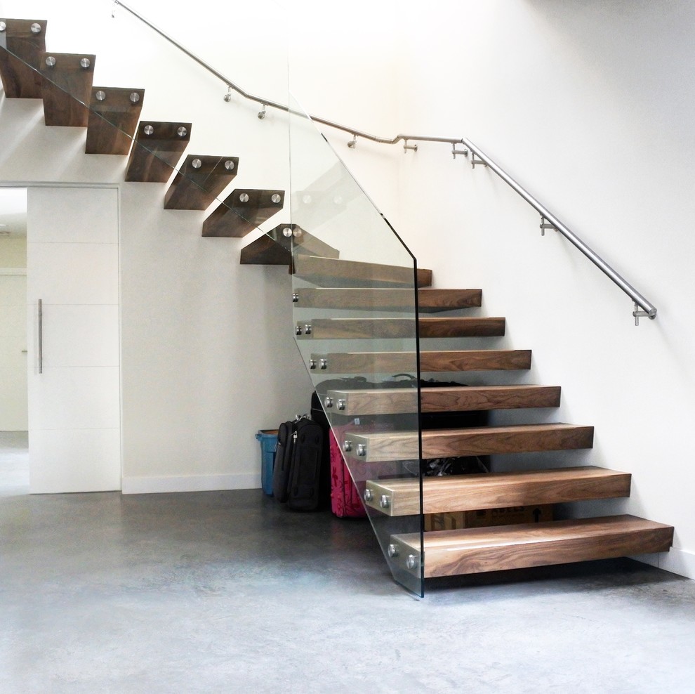 На фото: большая изогнутая лестница в современном стиле с деревянными ступенями и стеклянными перилами без подступенок с