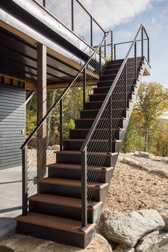 Aménagement d'un grand escalier droit montagne avec des marches en bois, des contremarches en bois et un garde-corps en câble.