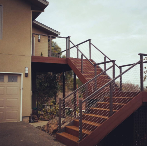 Diseño de escalera curva clásica de tamaño medio con escalones de madera, contrahuellas de madera y barandilla de metal