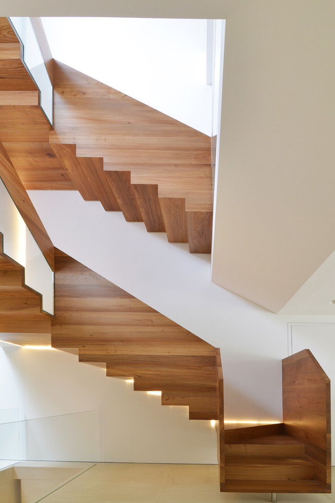 This is an example of a large contemporary wood u-shaped staircase in London with wood risers.