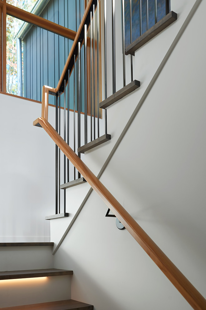 На фото: п-образная лестница в стиле модернизм с деревянными ступенями, крашенными деревянными подступенками и металлическими перилами с
