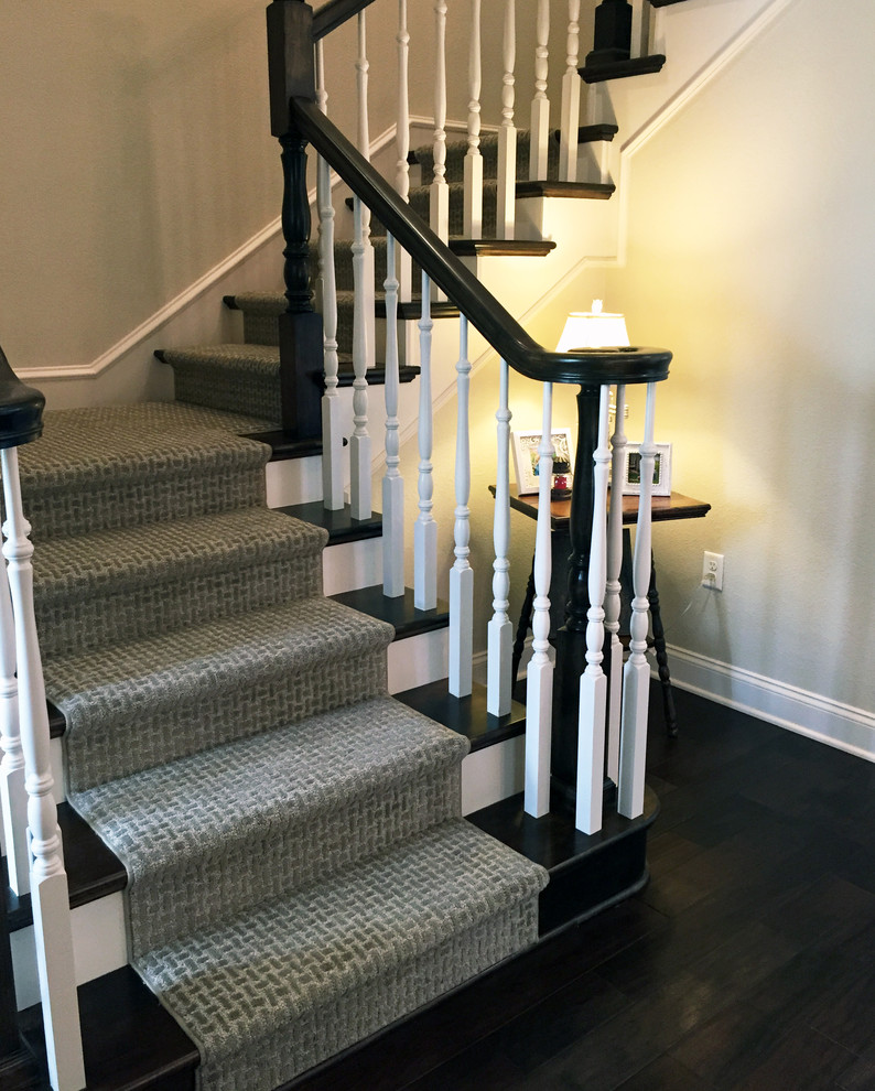 Cette photo montre un escalier chic en L de taille moyenne avec des marches en moquette, des contremarches en moquette et un garde-corps en bois.