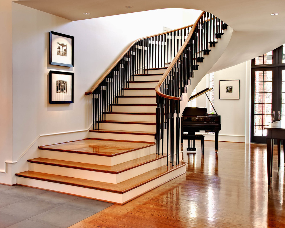Elegant wooden curved staircase photo in Charlotte with painted risers