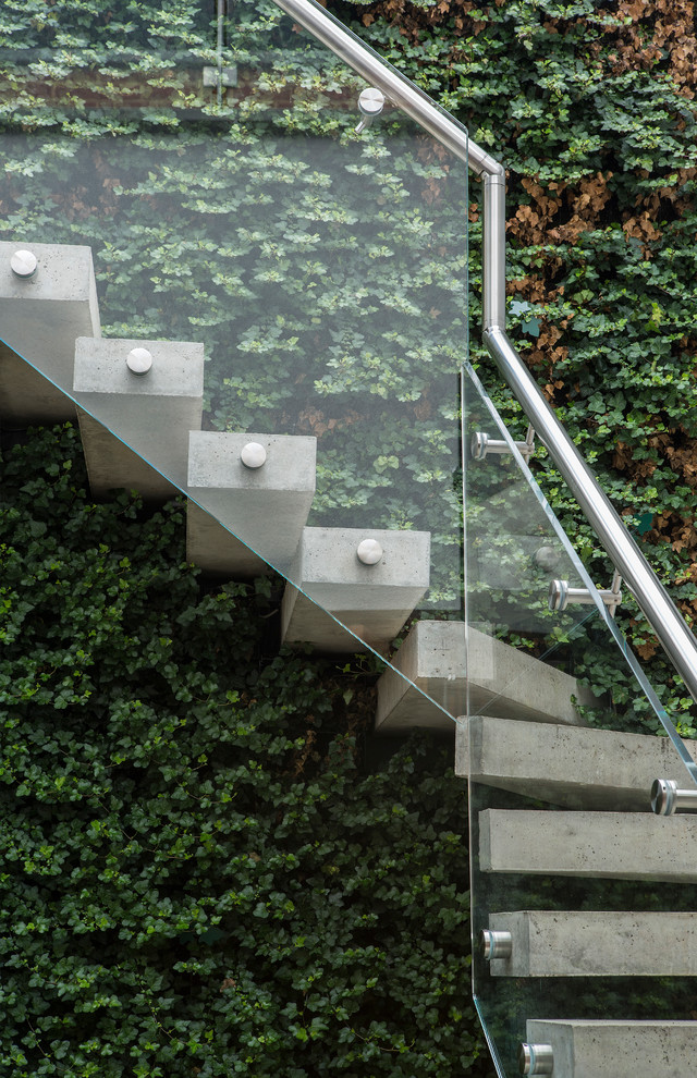 Modern inredning av en betongtrappa, med öppna sättsteg och räcke i glas