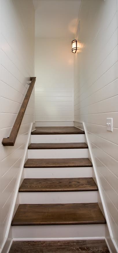 This is an example of a medium sized beach style wood l-shaped wood railing staircase in Other with painted wood risers.