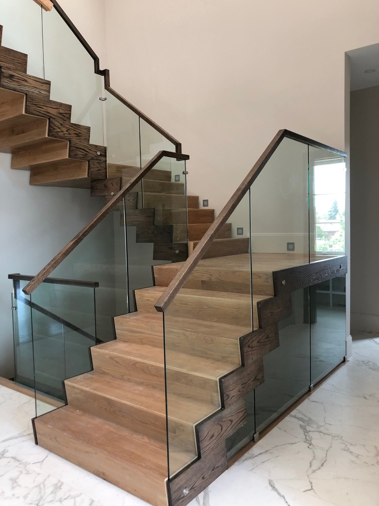 Ejemplo de escalera en U moderna de tamaño medio con escalones de madera, contrahuellas de madera y barandilla de vidrio
