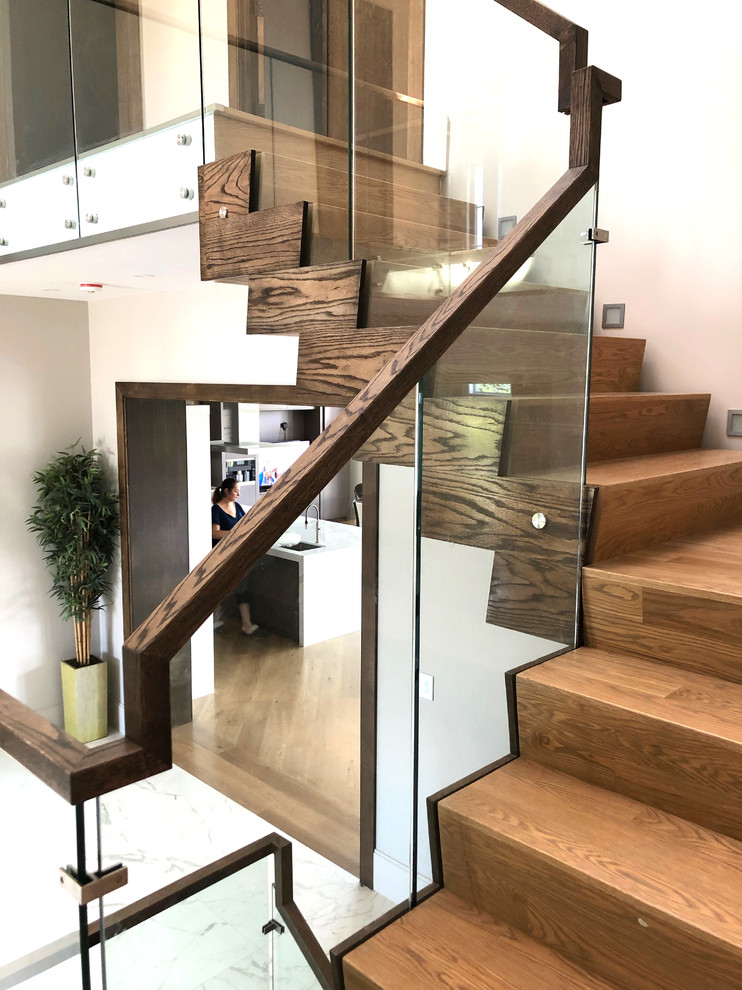 На фото: п-образная деревянная лестница среднего размера в стиле модернизм с деревянными ступенями и стеклянными перилами