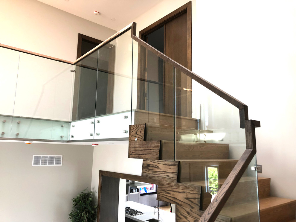 Inspiration for a medium sized modern wood u-shaped glass railing staircase in Toronto with wood risers.
