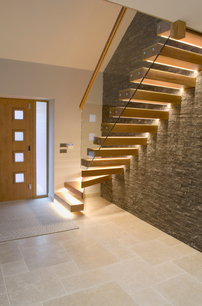 На фото: большая лестница на больцах в современном стиле с деревянными ступенями и стеклянными перилами без подступенок с