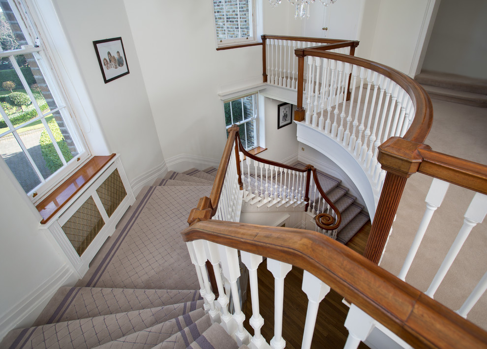 Foto på en stor vintage svängd trappa, med heltäckningsmatta och sättsteg med heltäckningsmatta