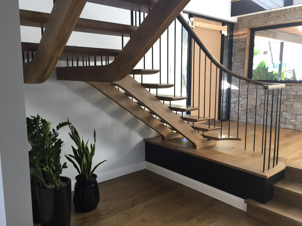 Réalisation d'un grand escalier sans contremarche vintage en L avec des marches en bois, un garde-corps en métal et boiseries.