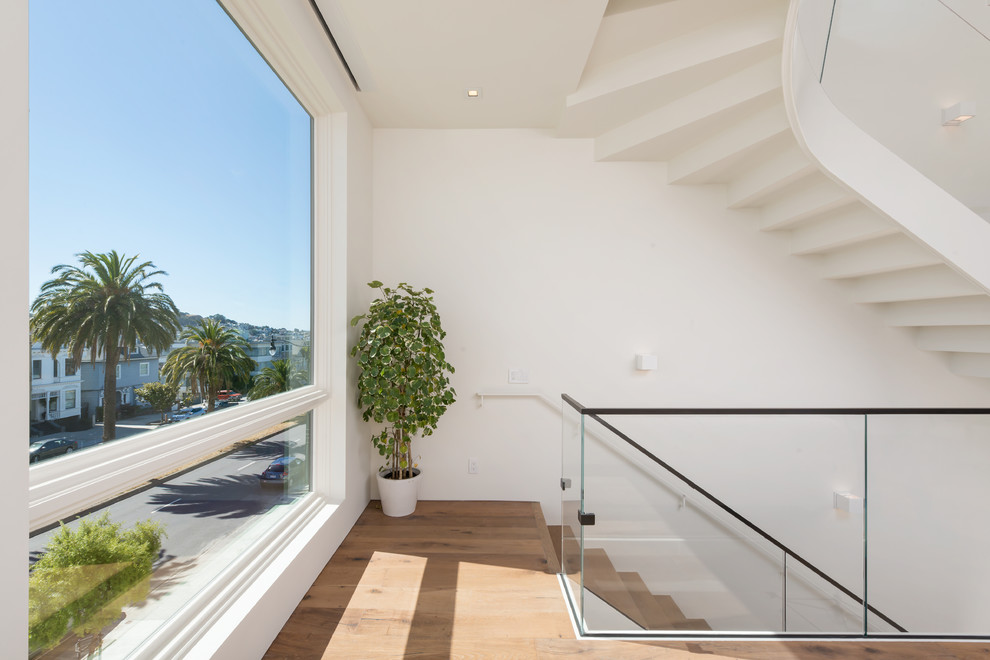 Ejemplo de escalera suspendida contemporánea de tamaño medio con escalones de madera, contrahuellas de madera y barandilla de vidrio