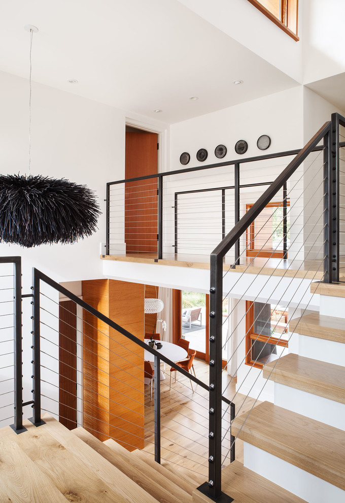 На фото: п-образная лестница в современном стиле с деревянными ступенями, крашенными деревянными подступенками и перилами из тросов