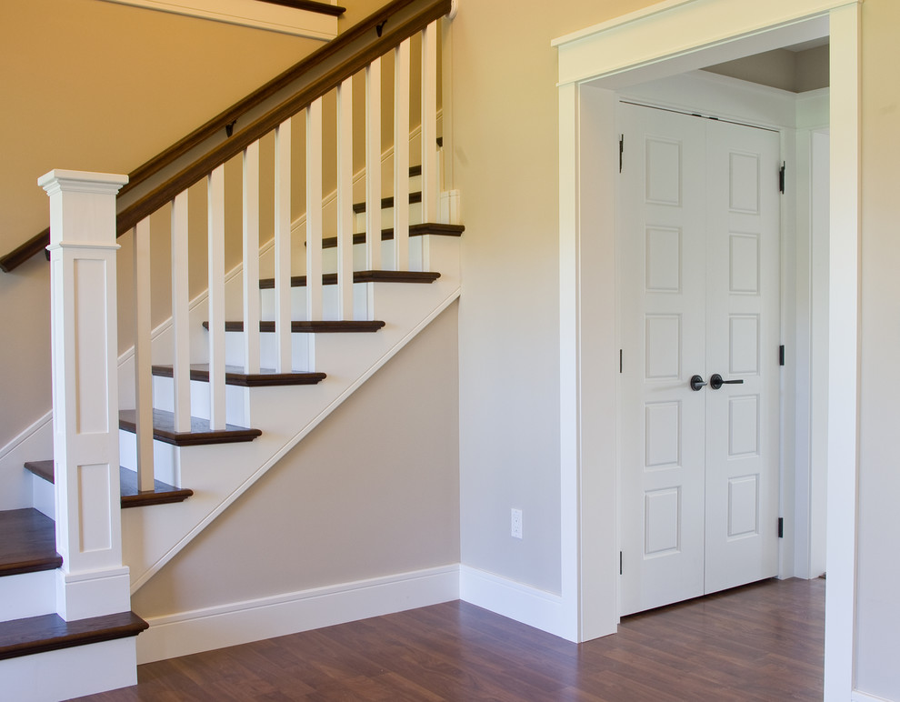 Diseño de escalera en L de estilo americano con escalones de madera, contrahuellas de madera pintada y barandilla de madera