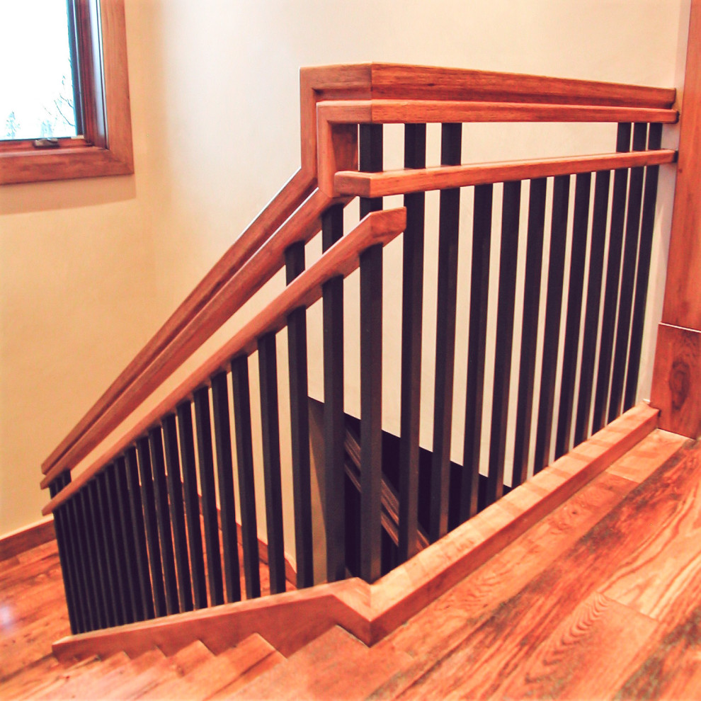 Diseño de escalera actual de tamaño medio con escalones de madera, contrahuellas de madera y barandilla de metal