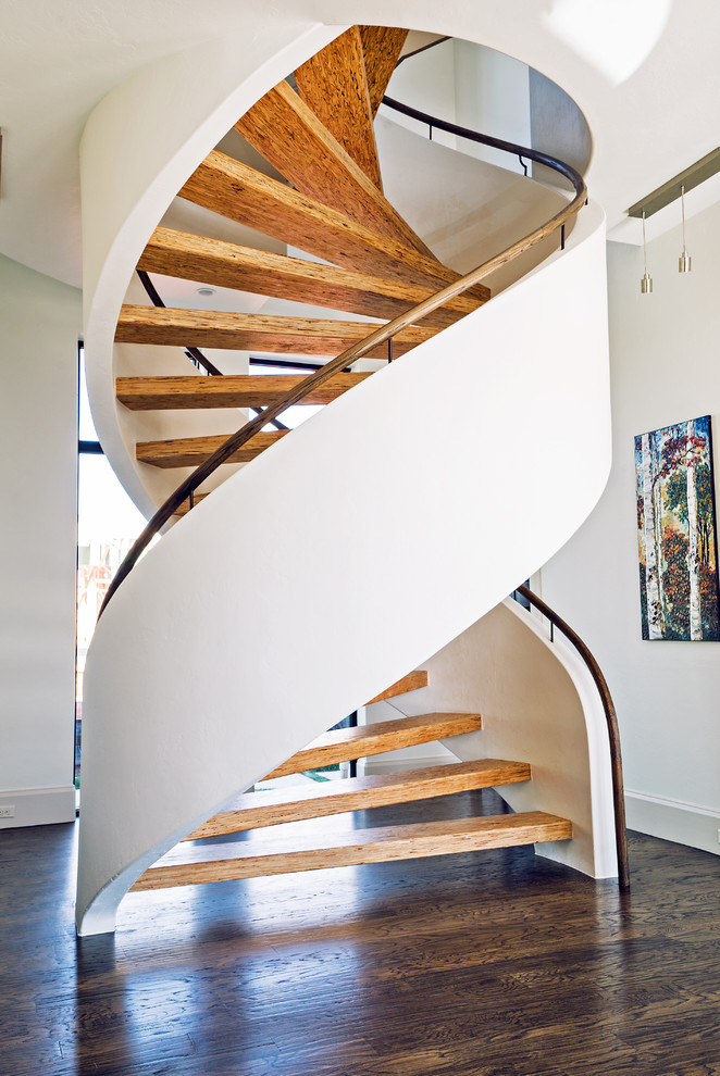 Пример оригинального дизайна: огромная изогнутая деревянная лестница в современном стиле с деревянными ступенями