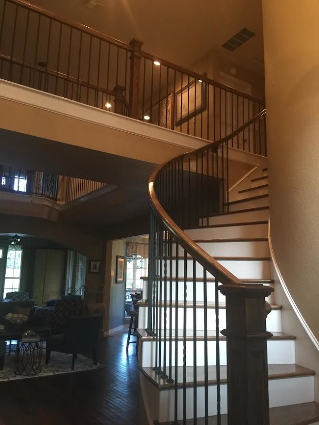 Large trendy wooden curved metal railing staircase photo in Dallas with painted risers