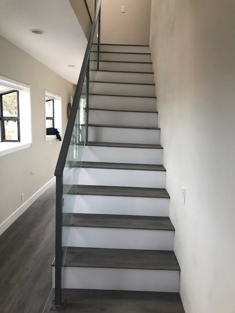 Example of a large trendy wooden straight glass railing staircase design in San Diego with painted risers