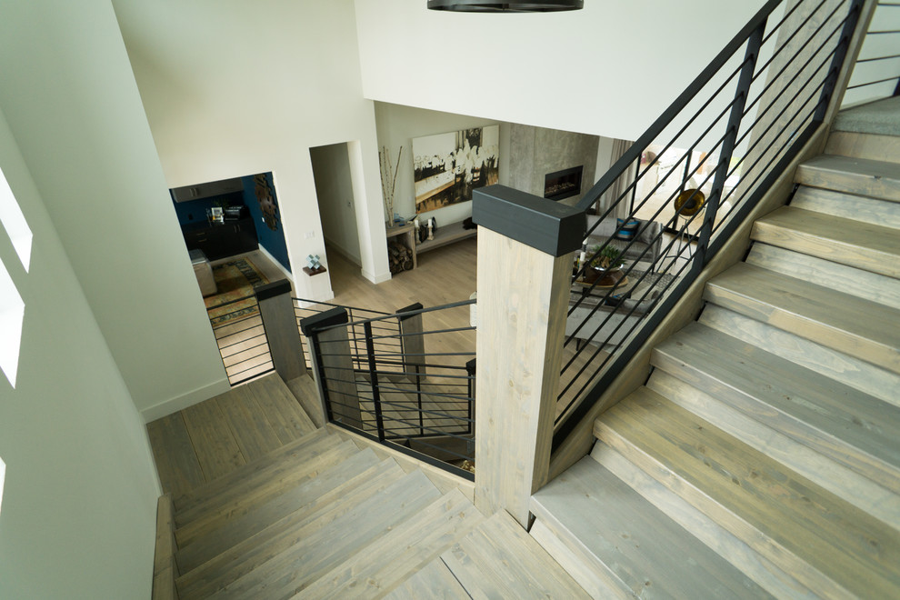 Cette photo montre un grand escalier sans contremarche tendance en U avec des marches en bois et un garde-corps en métal.
