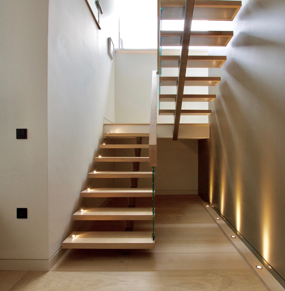 This is an example of a large contemporary wood floating wood railing staircase in London with open risers.