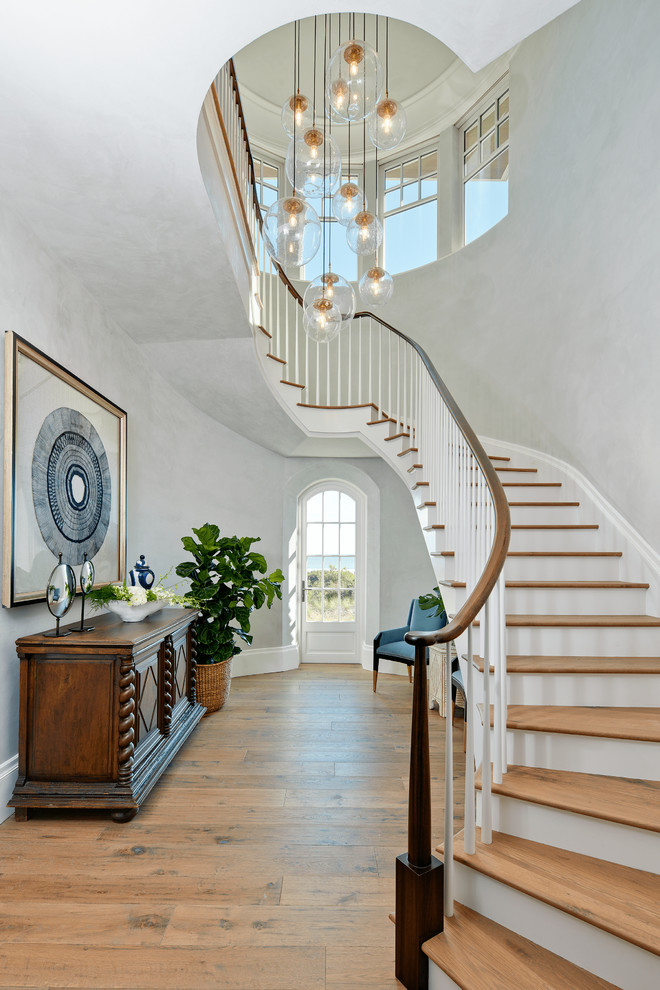 Источник вдохновения для домашнего уюта: изогнутая лестница в морском стиле с деревянными ступенями, крашенными деревянными подступенками и деревянными перилами