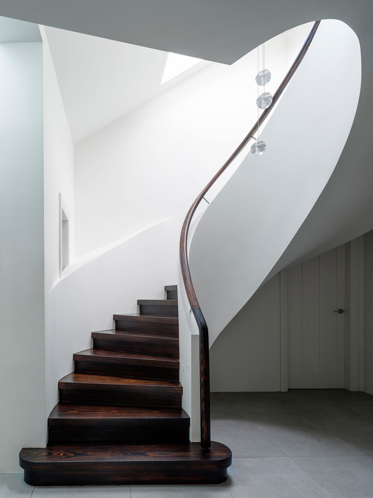Свежая идея для дизайна: изогнутая деревянная лестница в стиле неоклассика (современная классика) с деревянными ступенями - отличное фото интерьера