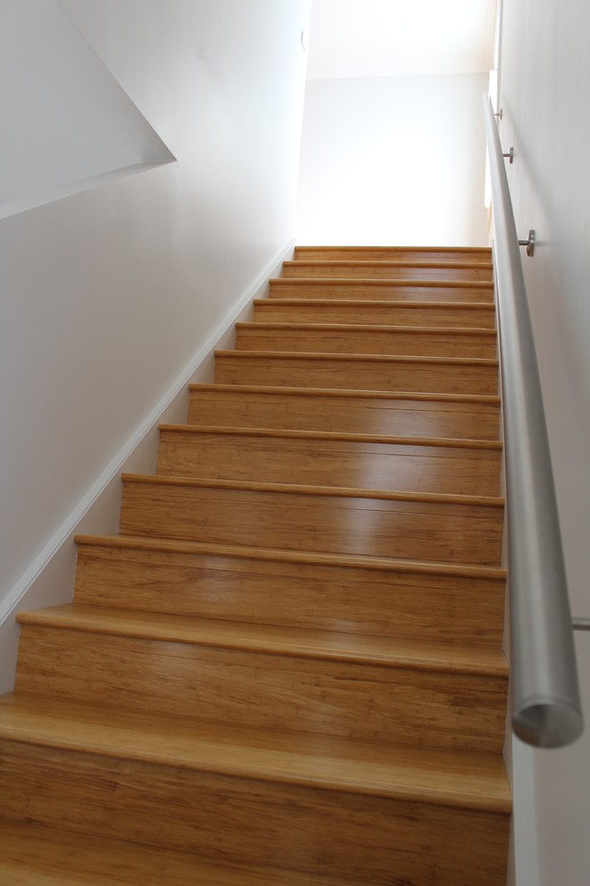 Aménagement d'un petit escalier droit moderne avec des marches en bois, des contremarches en bois et un garde-corps en métal.