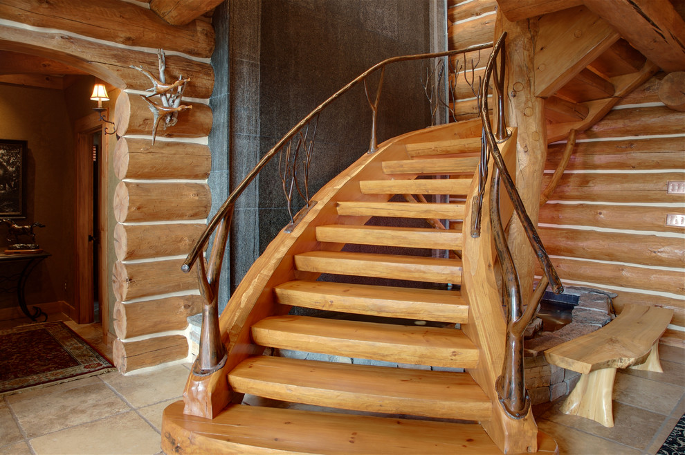 Imagen de escalera curva rústica grande sin contrahuella con escalones de madera y barandilla de madera