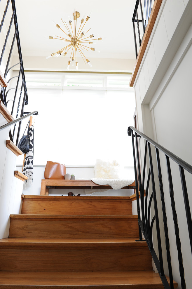 Imagen de escalera en U retro de tamaño medio con escalones de madera, contrahuellas de madera y barandilla de metal