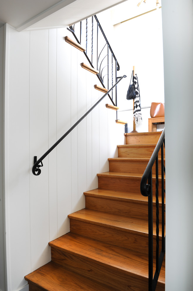Photo of a medium sized retro wood u-shaped metal railing staircase in Vancouver with wood risers.