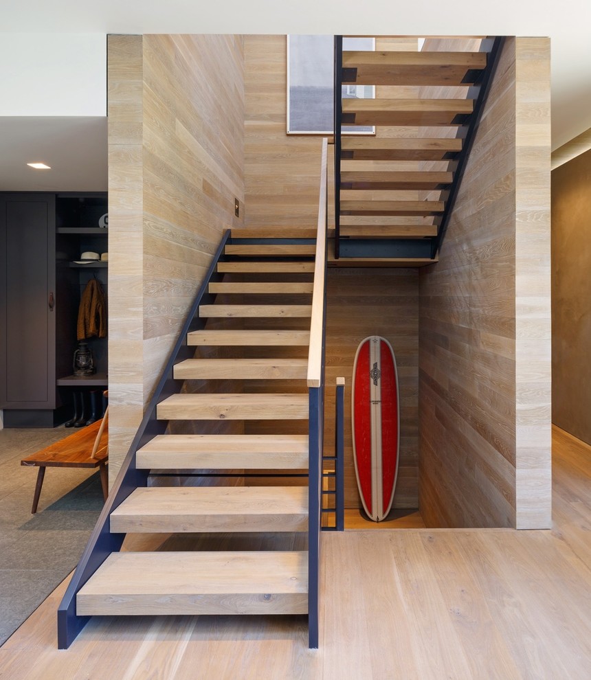 Imagen de escalera suspendida moderna sin contrahuella con escalones de madera y barandilla de metal