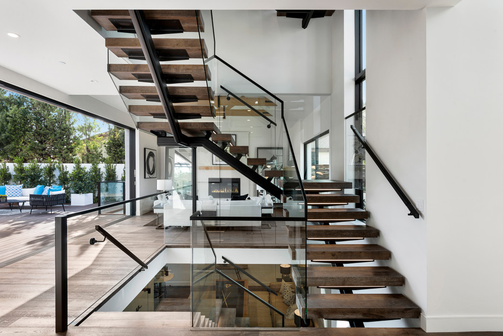 Diseño de escalera suspendida costera grande con escalones de madera y barandilla de vidrio