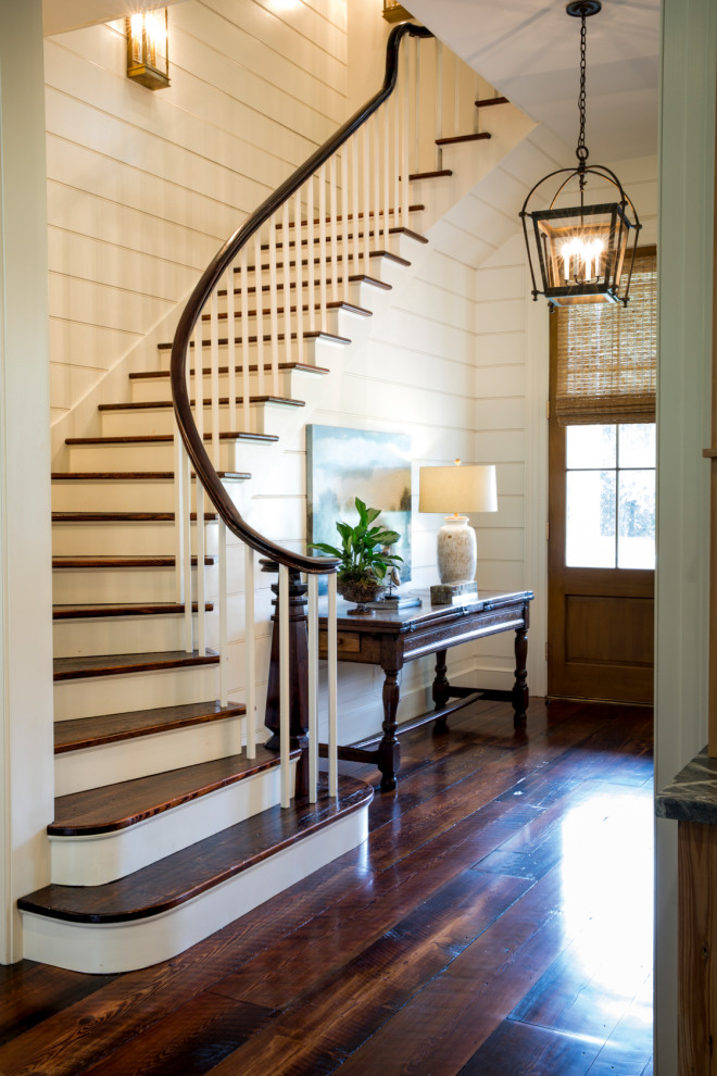 Idée de décoration pour un escalier courbe tradition de taille moyenne avec des marches en bois, des contremarches en bois, un garde-corps en bois et du lambris de bois.