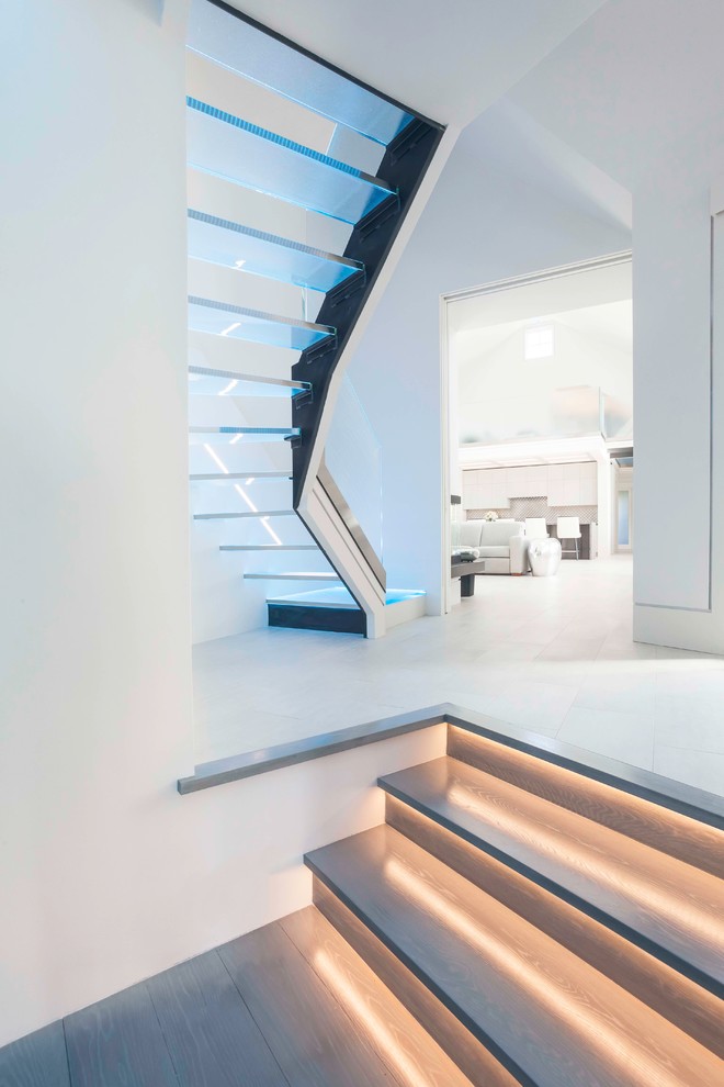 Cette photo montre un grand escalier sans contremarche courbe moderne avec des marches en verre.
