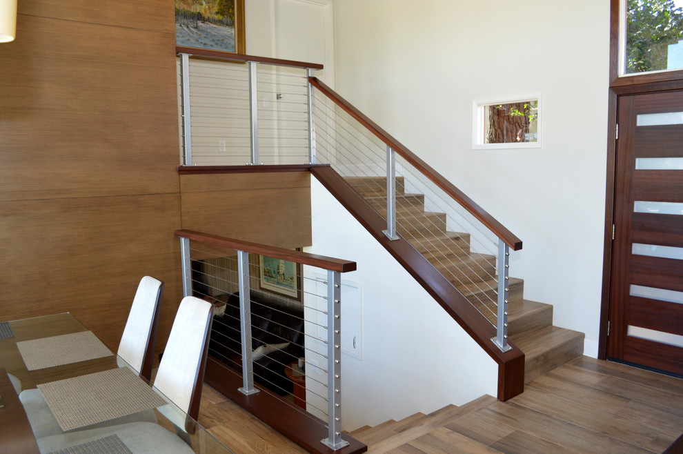 Diseño de escalera en L retro de tamaño medio con escalones con baldosas, contrahuellas con baldosas y/o azulejos y barandilla de varios materiales