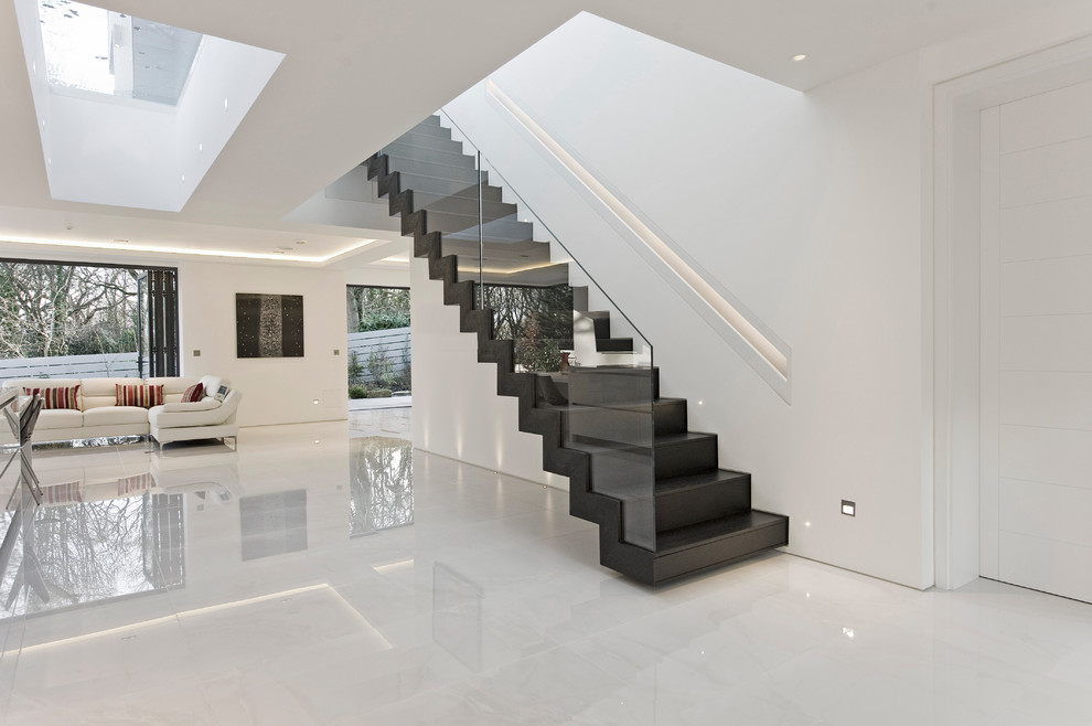 Large contemporary wood floating glass railing staircase in London with wood risers.