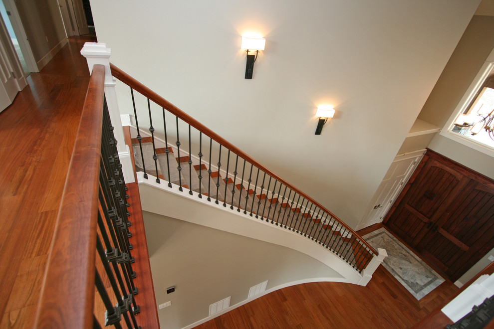 Стильный дизайн: большая изогнутая лестница в стиле неоклассика (современная классика) с ступенями с ковровым покрытием и крашенными деревянными подступенками - последний тренд