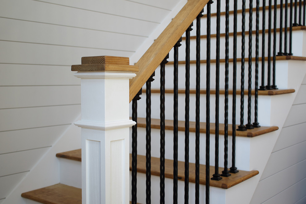 На фото: большая угловая лестница в классическом стиле с деревянными ступенями, крашенными деревянными подступенками и перилами из смешанных материалов с